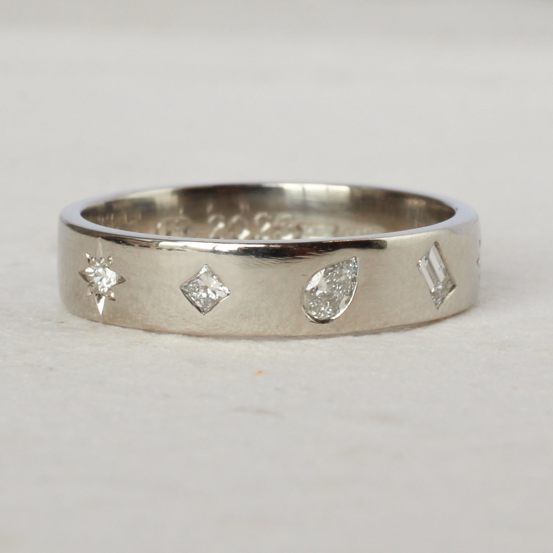 Silver ring with diamond-shaped cutouts on a light gray background