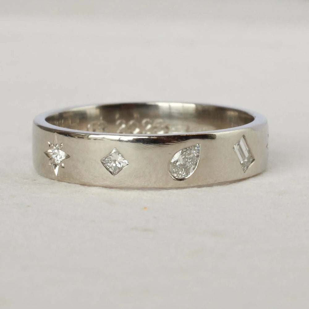 Silver ring with diamond-shaped cutouts on a light gray background