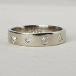 Silver ring with diamond-shaped cutouts on a light gray background