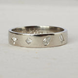 Silver ring with diamond-shaped cutouts on a light gray background