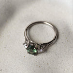 Silver ring with green gemstone on a textured white surface