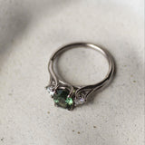 Silver ring with green gemstone on a textured white surface
