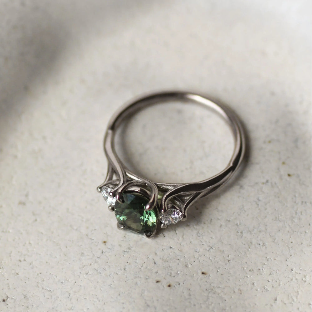 Silver ring with green gemstone on a textured white surface