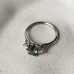 Silver ring with green gemstone on a textured white surface