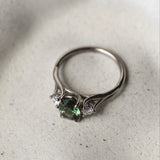 Silver ring with green gemstone on a textured white surface