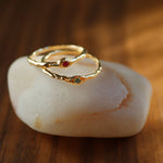 Gold ring with gemstones on a white stone against a wooden background