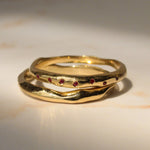 Gold ring with embedded red stones on a light background