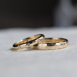 two bespoke wedding rings featuring hammered finish and blue sapphire with diamonds