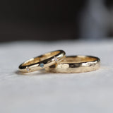 two bespoke wedding rings featuring hammered finish and blue sapphire with diamonds