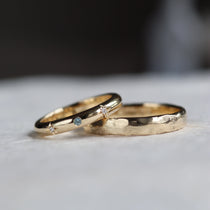 two bespoke wedding rings featuring hammered finish and blue sapphire with diamonds