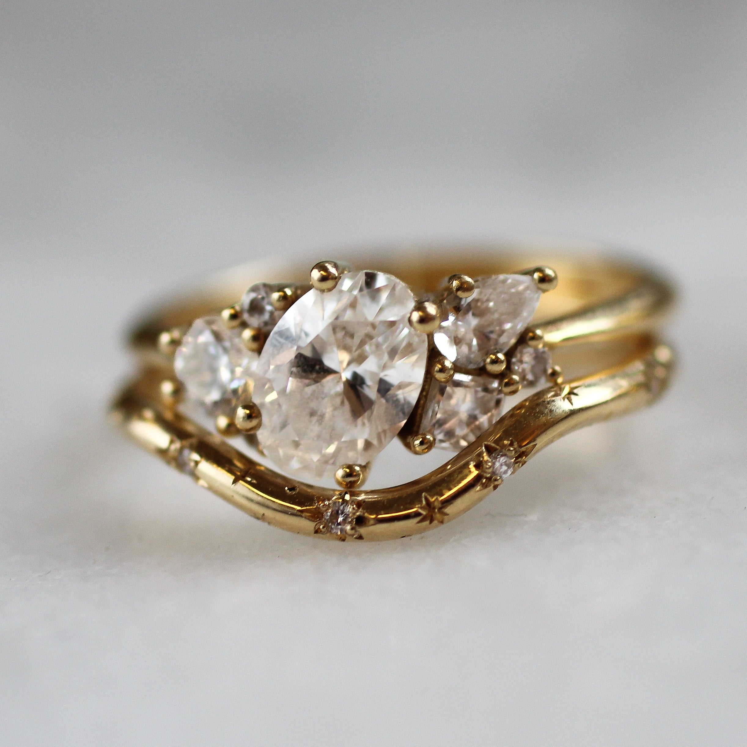 Gold ring with a large diamond and smaller stones on a light gray background