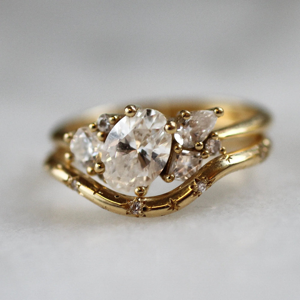 Gold ring with a large diamond and smaller stones on a light gray background
