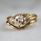 Gold ring with a large diamond and smaller stones on a light gray background