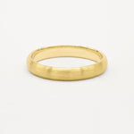 4mm wide yellow gold brushed wedding ring on a light gray background