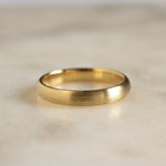 gold wedding band with brushed texture on marble surface