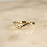 v shaped chevron wedding ring in gold on marble surface