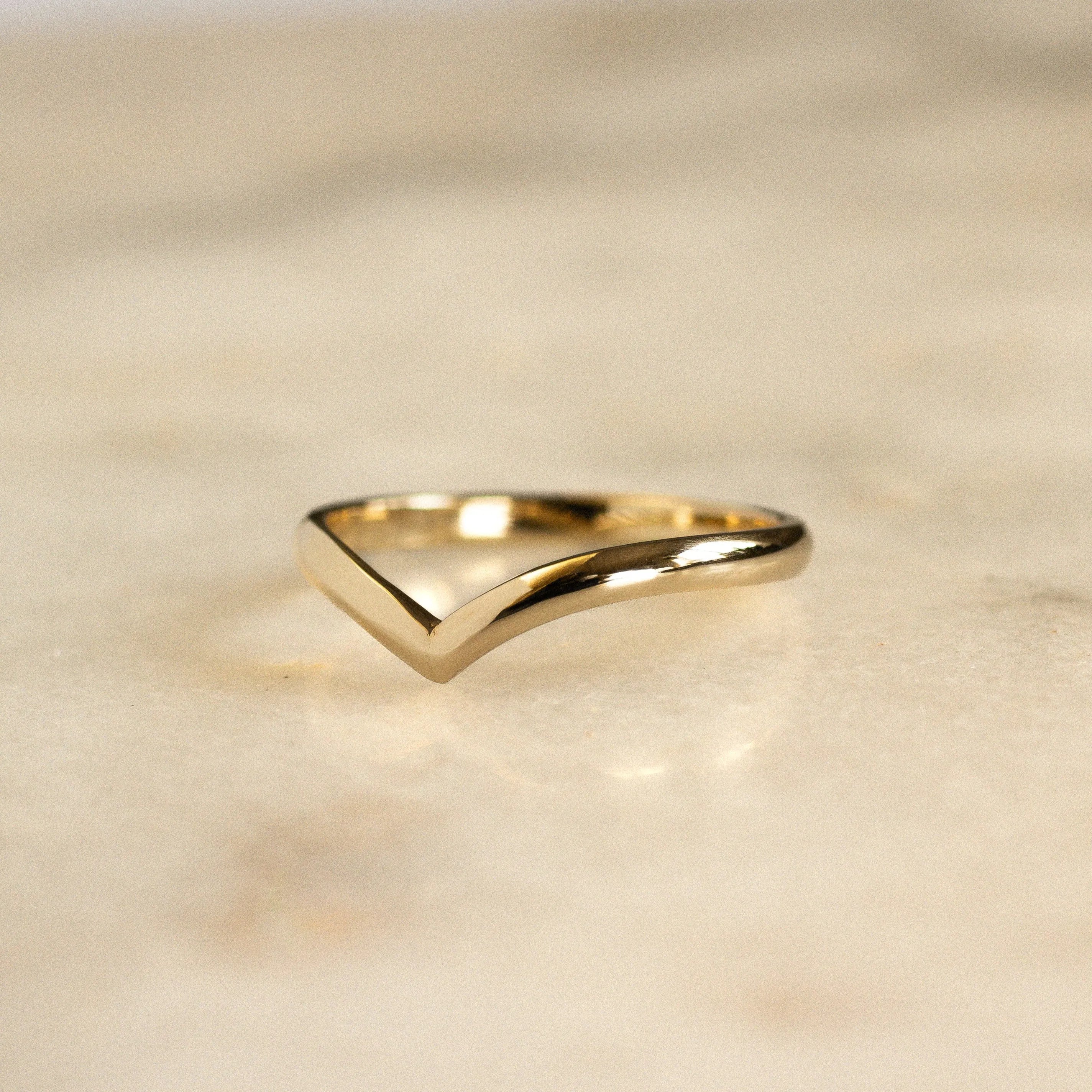 v shaped chevron wedding ring in gold on marble surface