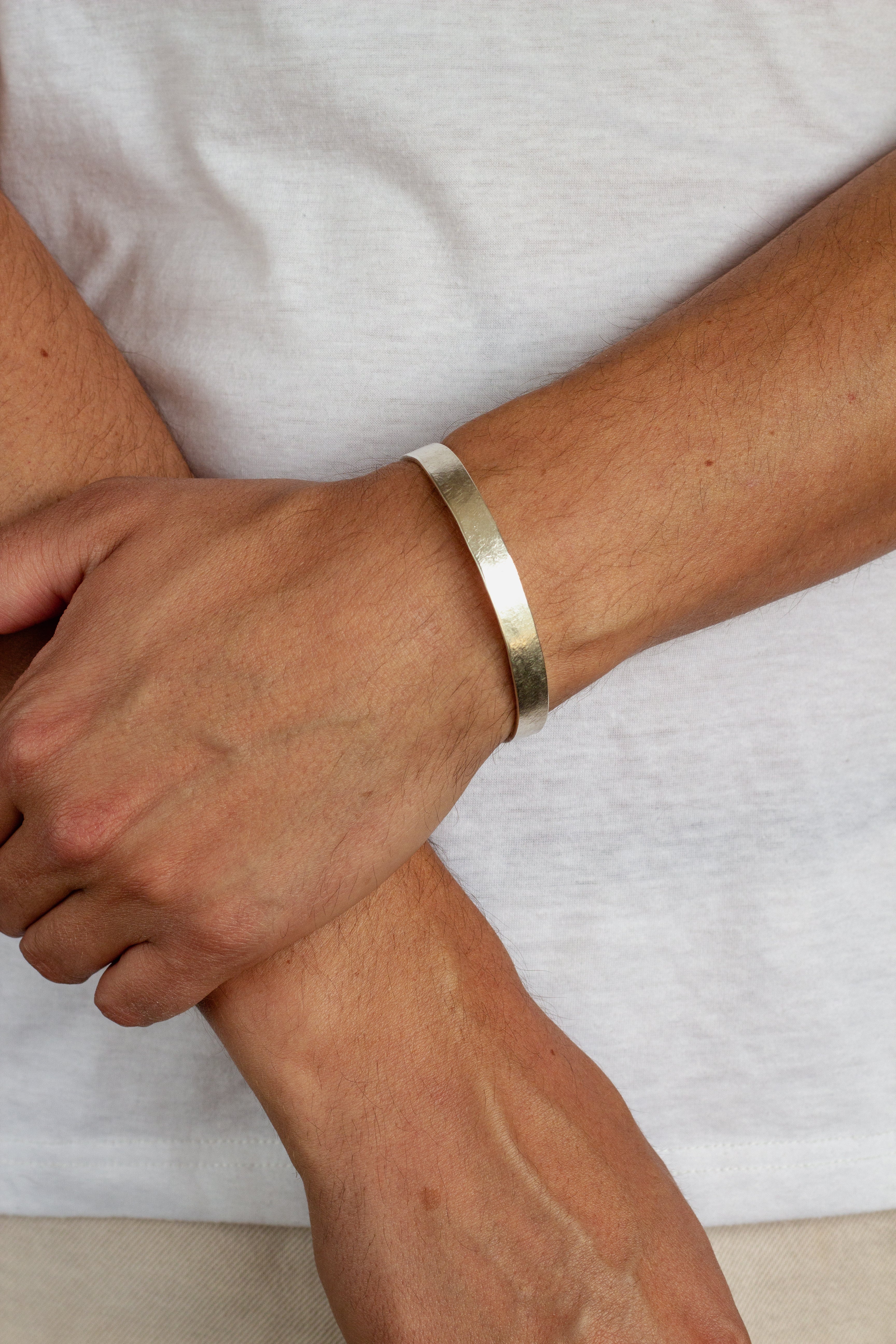 close up of tanned male arms wearing silver chunky bangle