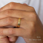 Close-up of a hand wearing a 18ct yellow gold ring with '5mm' text.