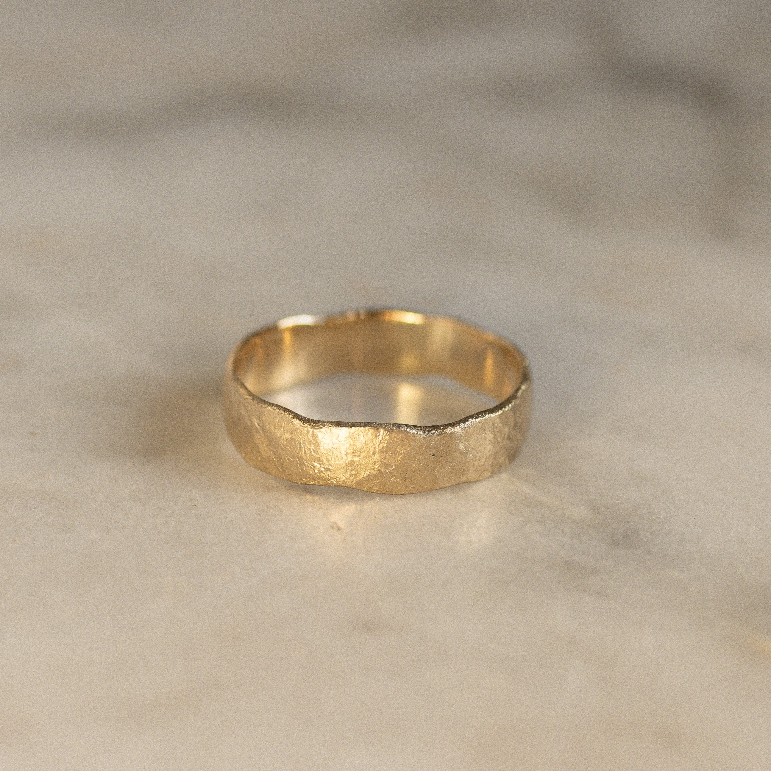 rustric wedding ring with uneven edges on marble surface