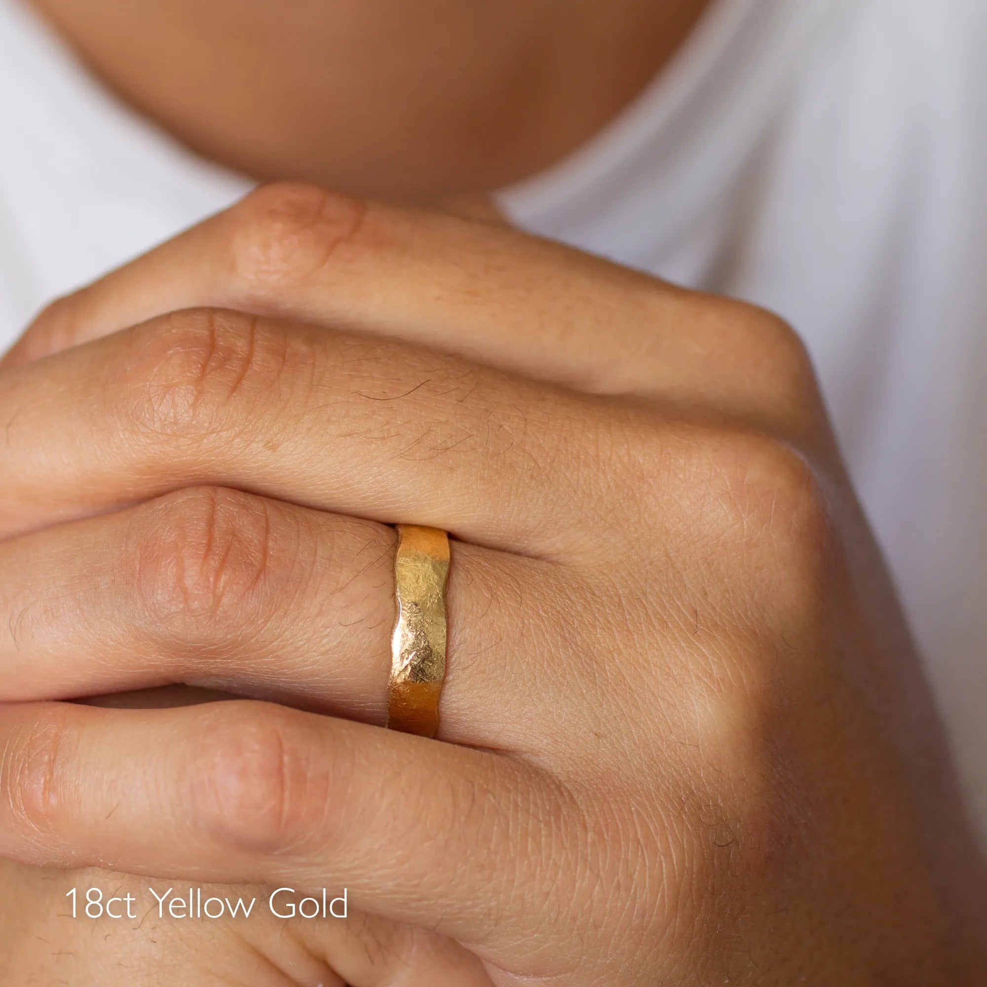 Gold ring on a person's finger with '18ct Yellow Gold' text