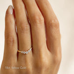 18ct yellow gold curved wedding ring with 5 diamonds on a hand against a beige background