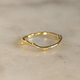 Gold tree branch ring on a marble surface