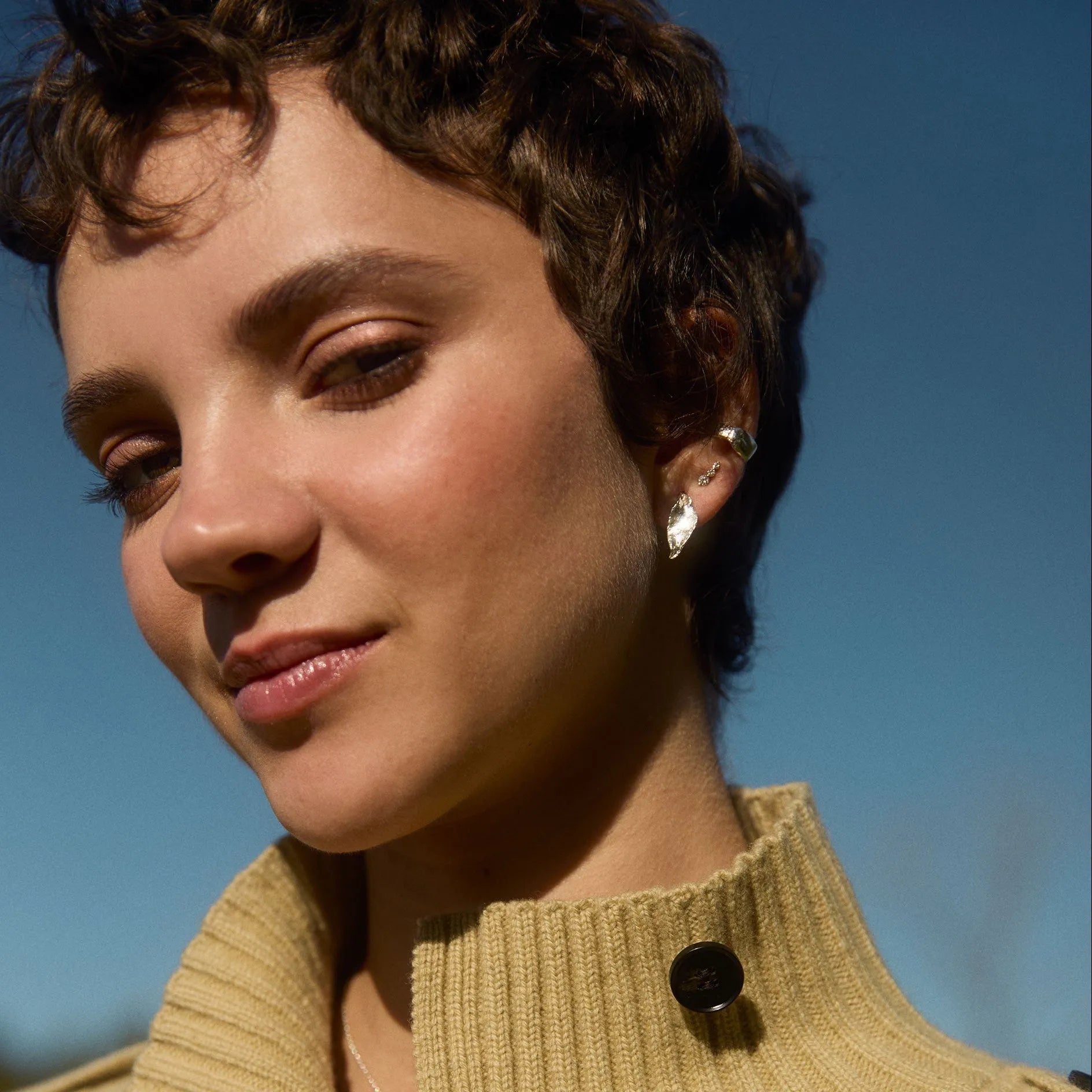woman with sky in background wearing silver stud leaf earrings