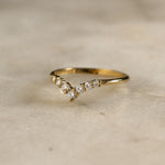 yellow gold chevron shaped wedding ring with 7 round diamonds on marble surface