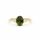 Gold engagement ring with a forest green sapphire and two smaller diamonds on a white background