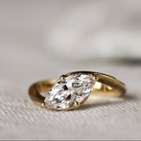 Gold ring with a marquise diamond on a textured fabric background