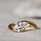 Gold ring with a marquise diamond on a textured fabric background