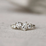 Diamond ring with round and pear diamonds in an asymmetric ensemble on a textured surface with a blurred background