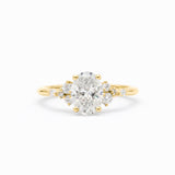 A yellow gold ring featuring a large oval-cut center diamond surrounded by smaller round diamonds on the shoulders, set against a clean white background.