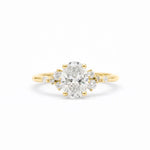A yellow gold ring featuring a large oval-cut center diamond surrounded by smaller round diamonds on the shoulders, set against a clean white background.