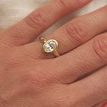 Gold ring with a diamond on a hand against a neutral background