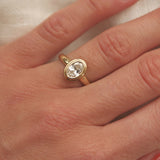 Gold ring with a diamond on a hand against a neutral background