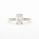 An oval-cut diamond solitaire ring in a four-prong setting on a polished silver-colored band, centered against a plain white background.