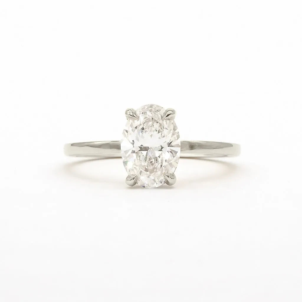 An oval-cut diamond solitaire ring in a four-prong setting on a polished silver-colored band, centered against a plain white background.
