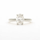 An oval-cut diamond solitaire ring in a four-prong setting on a polished silver-colored band, centered against a plain white background.