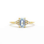 light blue sapphire engagement ring with diamond cluster on a white background