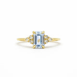 light blue sapphire engagement ring with diamond cluster on a white background
