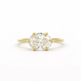 east-west set diamond engagement ring with oval diamond in gold on a white background
