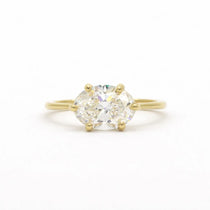 east-west set diamond engagement ring with oval diamond in gold on a white background
