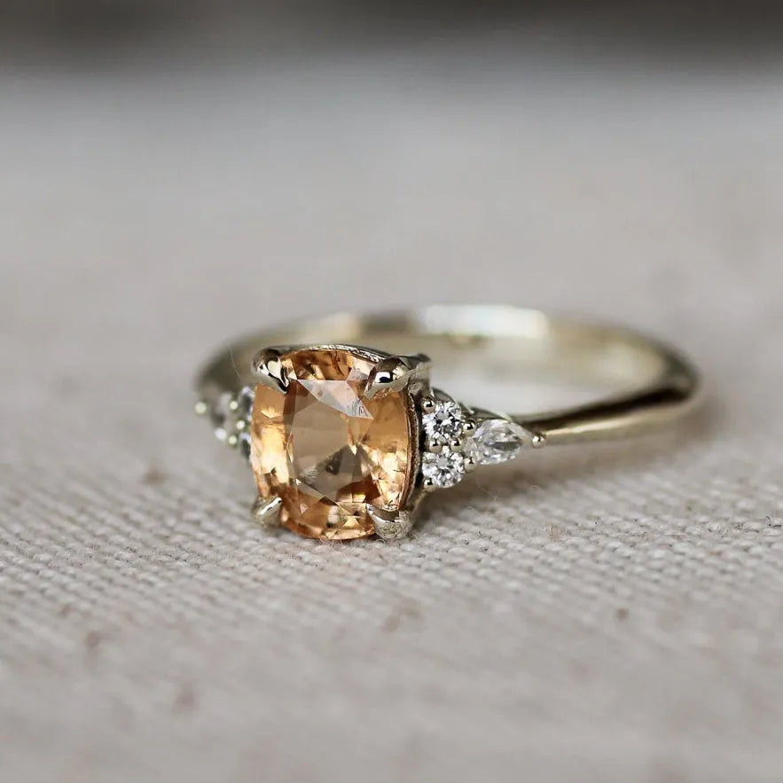 Silver ring with a peach-colored gemstone on a textured gray surface