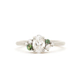 white gold diamond engagement ring with green sapphires on a white background