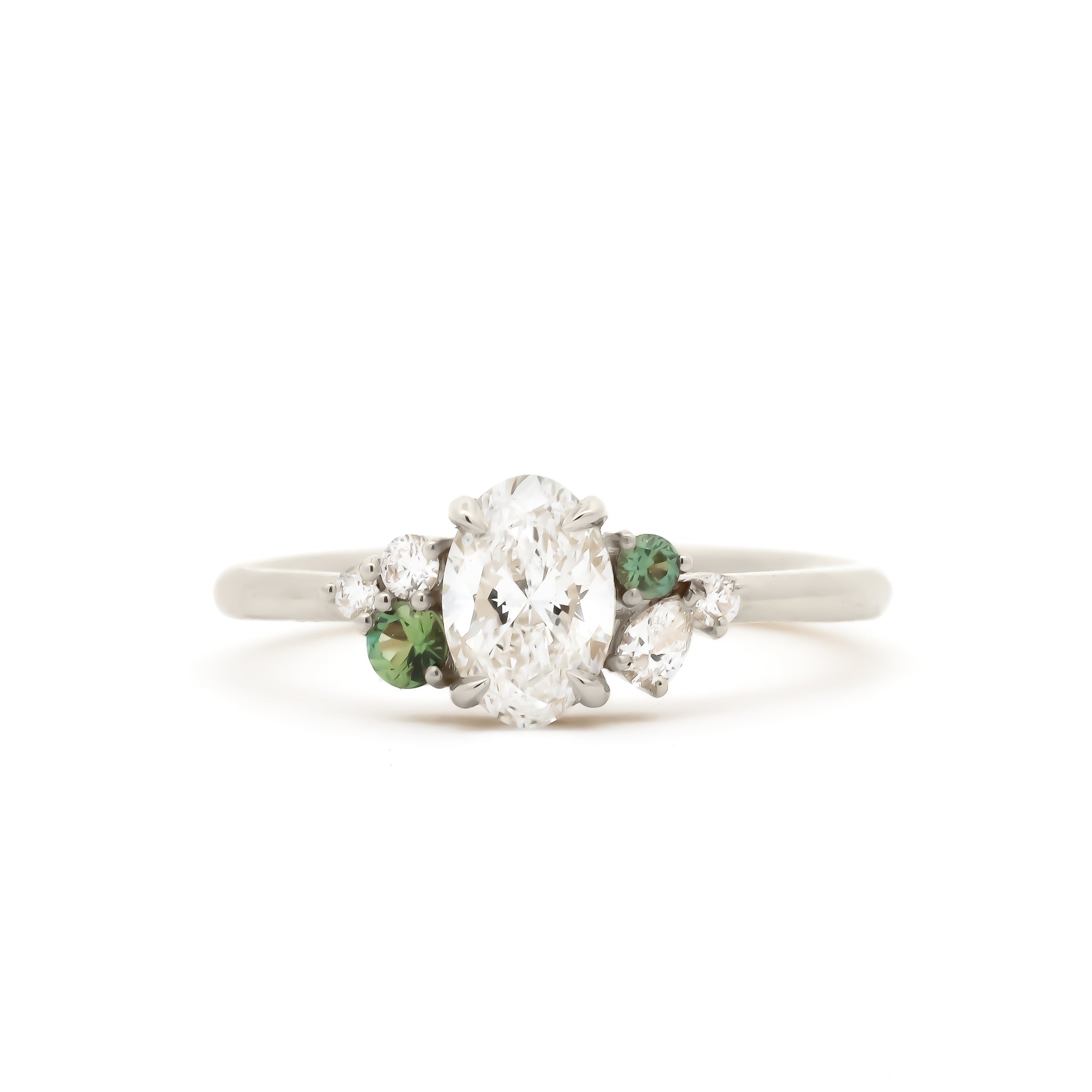 white gold diamond engagement ring with green sapphires on a white background