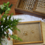 Gold engagement rings on a display tray with a jewelry box in the background