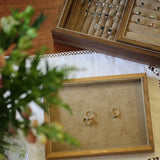 Gold engagement rings on a display tray with a jewelry box in the background