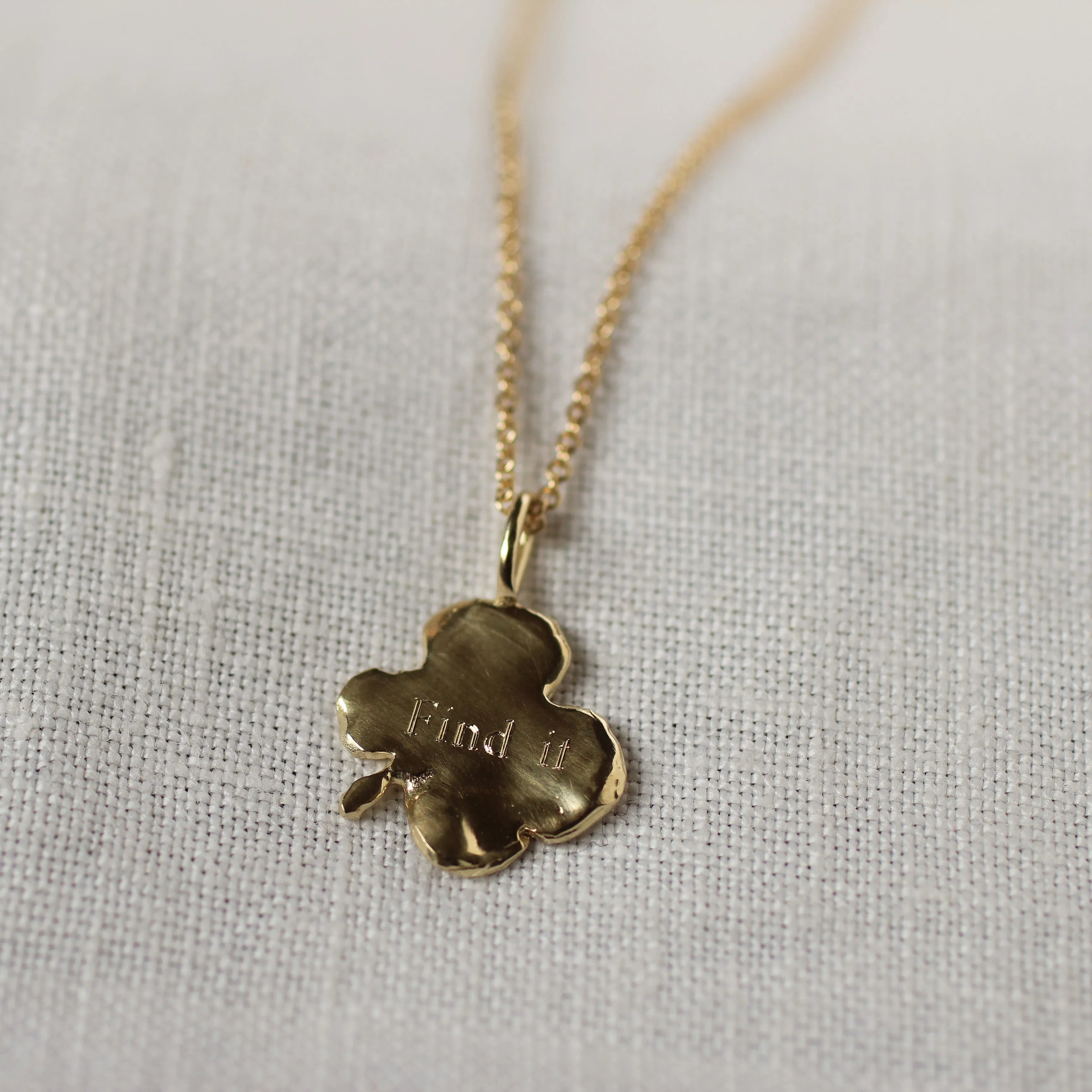back of gold 4 leaf clover necklace with 'Find it' engraved